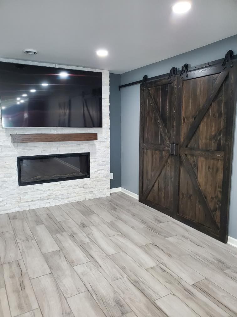 Modern room with white brick fireplace, wall-mounted TV, and rustic barn-style door on light wood flooring