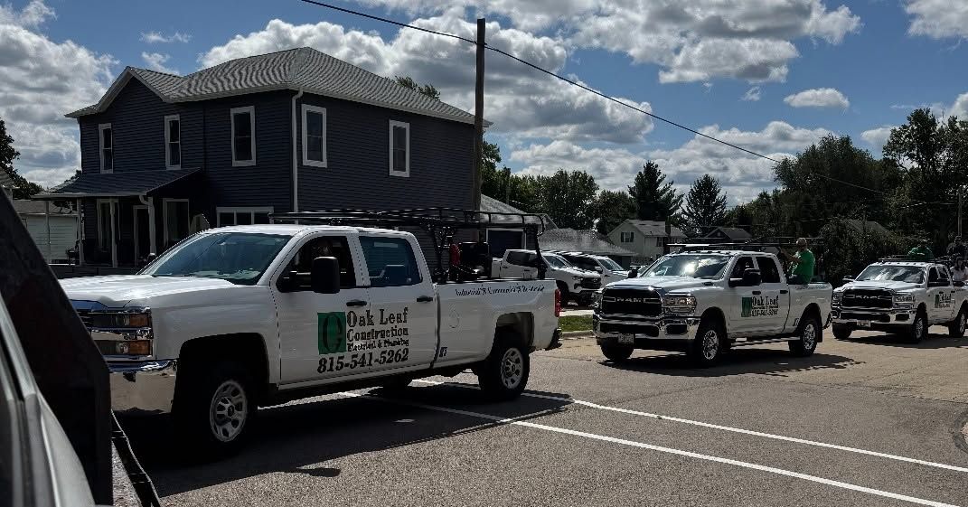White pickup trucks lined up in a parking lot beside a blue building under a partly cloudy sky.