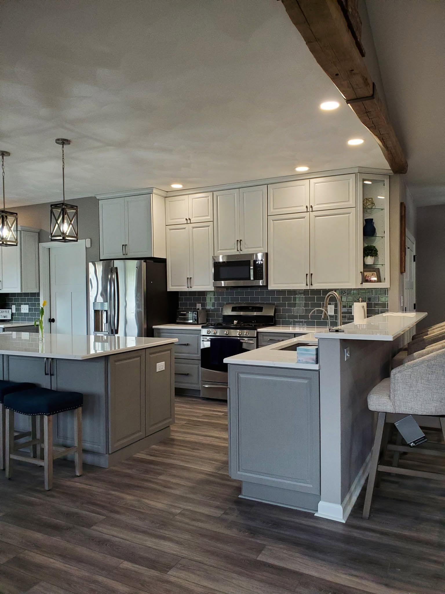 Modern kitchen with white cabinets, stainless appliances, island, and bar stools in a bright open layout