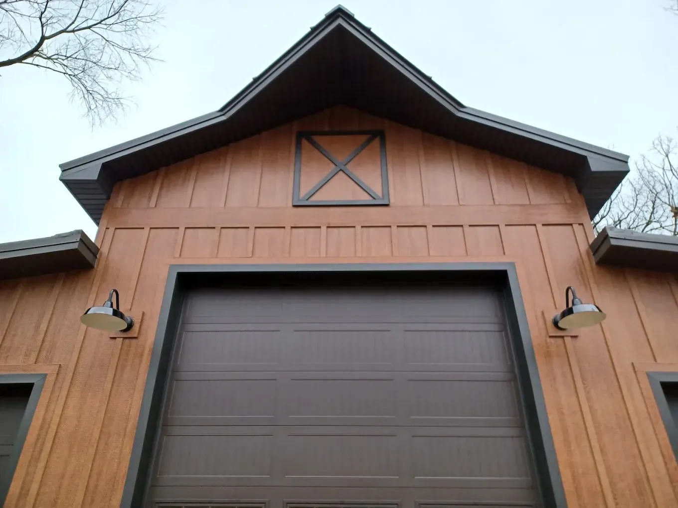 Wooden garage door on a barn-style building with brown siding and a peaked roof