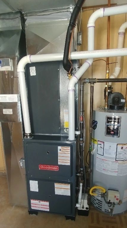 Basement HVAC furnace and water heater with white ductwork and pipes