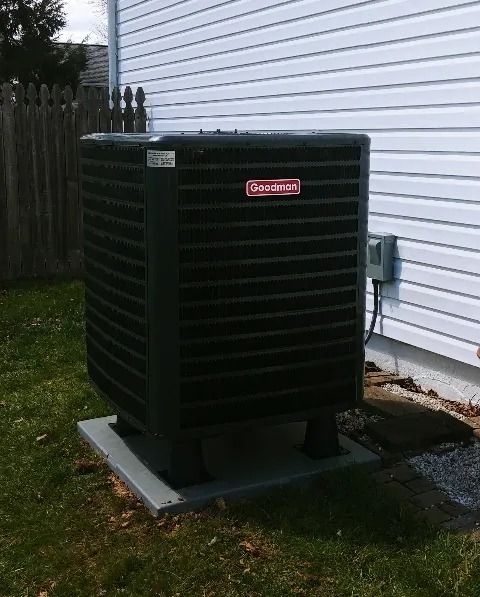 Outdoor Lennox air conditioner unit beside a white house and wooden fence
