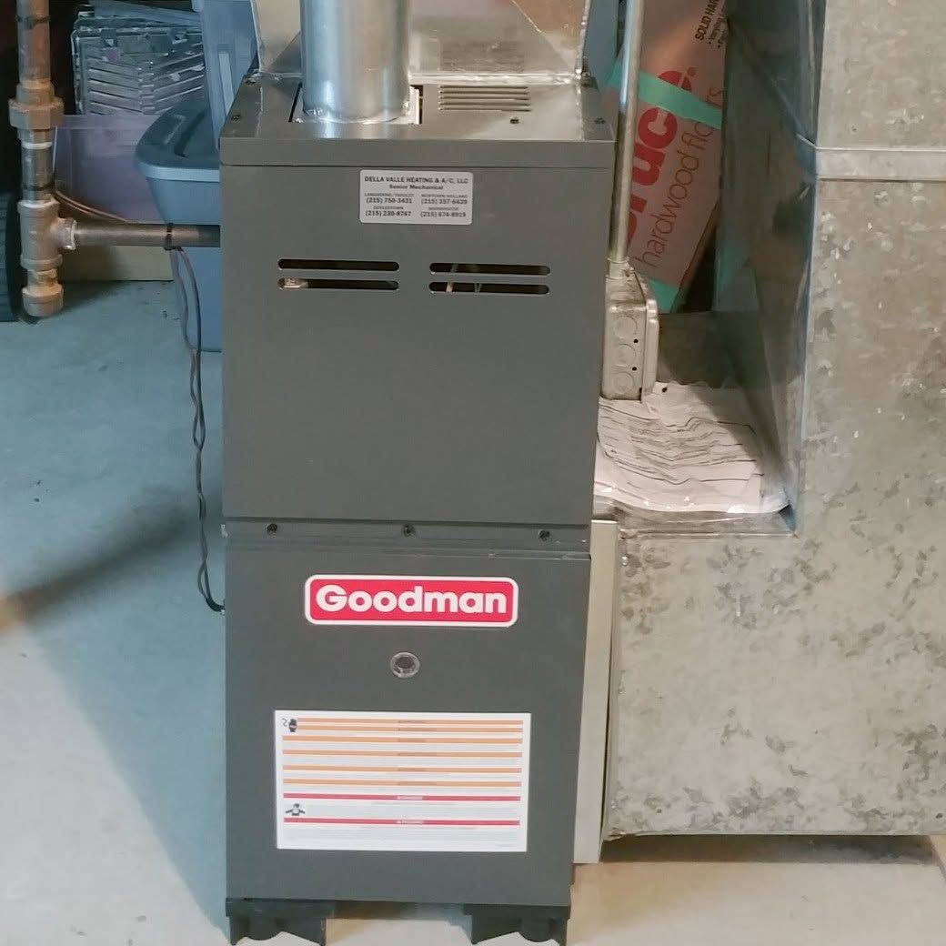 Gray Goodman furnace in a basement utility area with vents and ductwork.