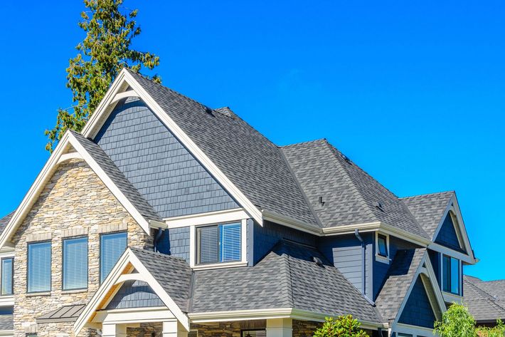 a large house with a gray roof and a blue sky in the background