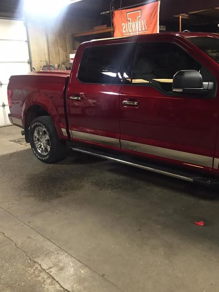 Red pickup truck with chrome accents parked in a garage with a Tennessee Volunteers banner.