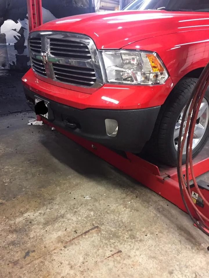 Red Dodge Ram pickup truck on a lift in a garage, front view.