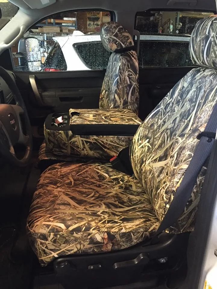 Camo seat covers inside the cab of a truck, covering the seats and center console.