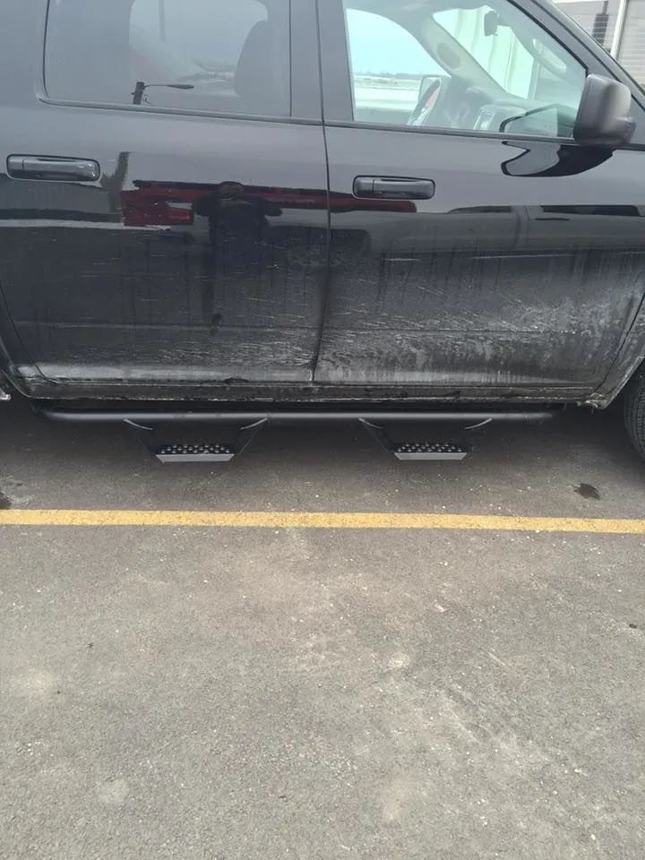 Black pickup truck with black running boards, parked on concrete.