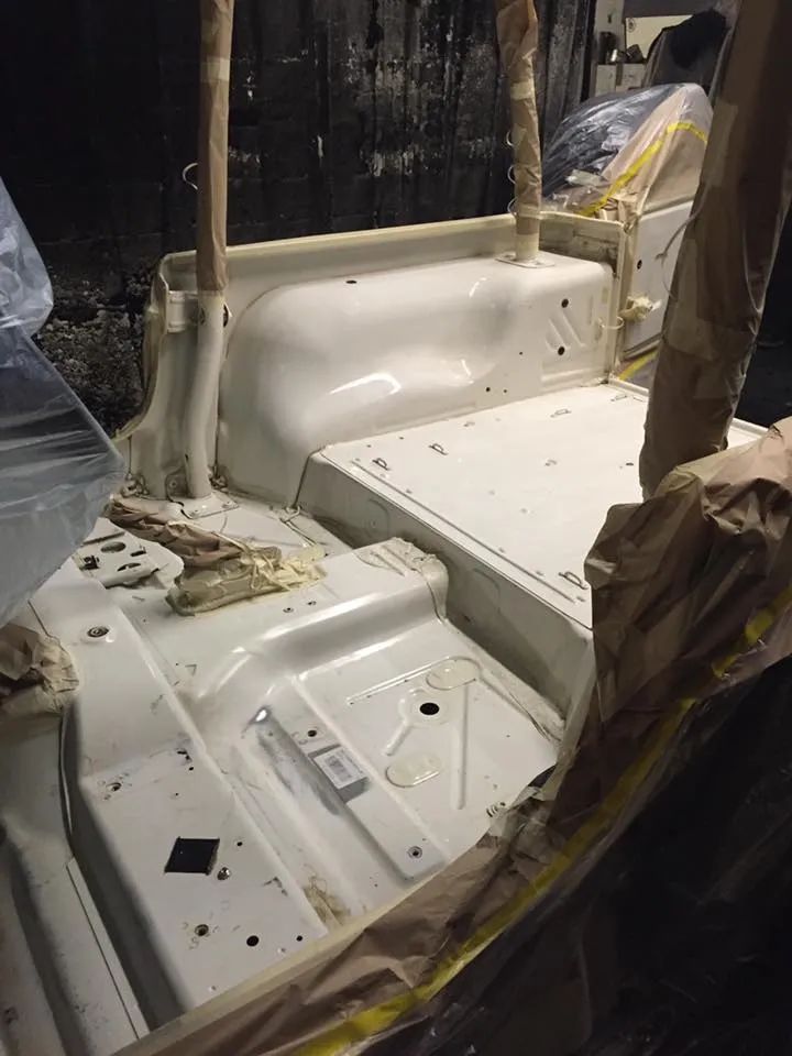 White interior of a vehicle, possibly a Jeep, masked for painting.