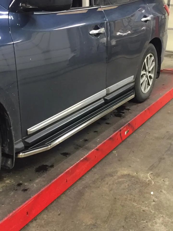Blue SUV with running boards on a red platform.