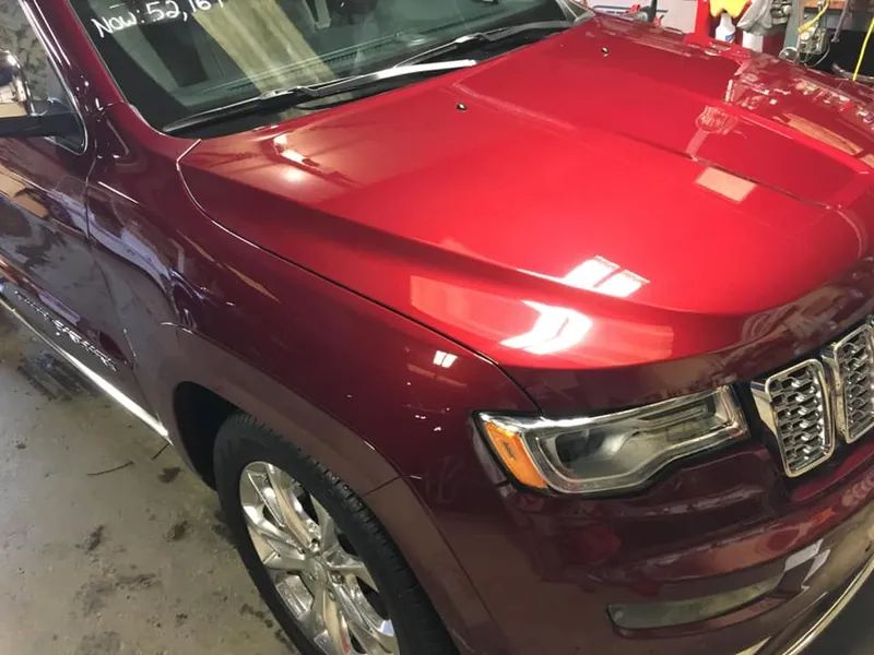 Red Jeep Grand Cherokee SUV with shiny paint, chrome accents, and a glass windshield.