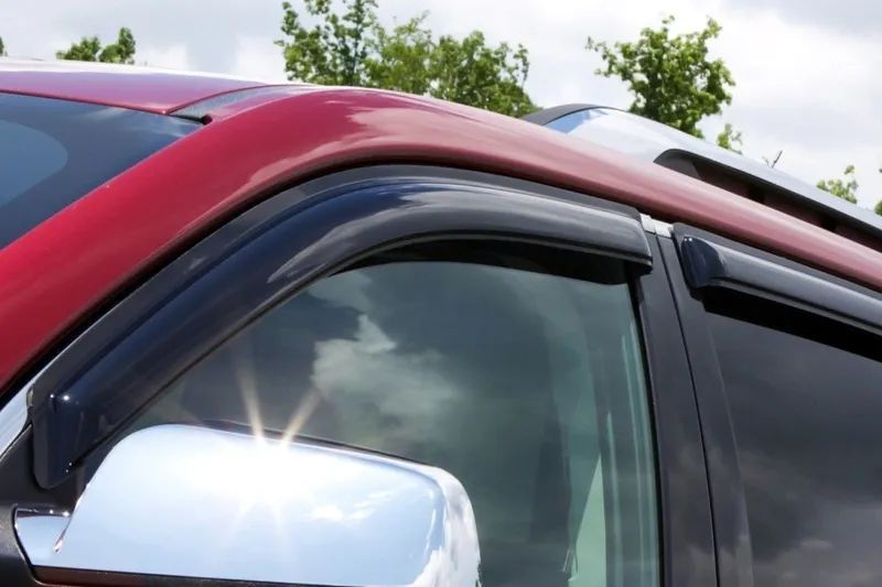 Red car with black window visors; side mirror visible.