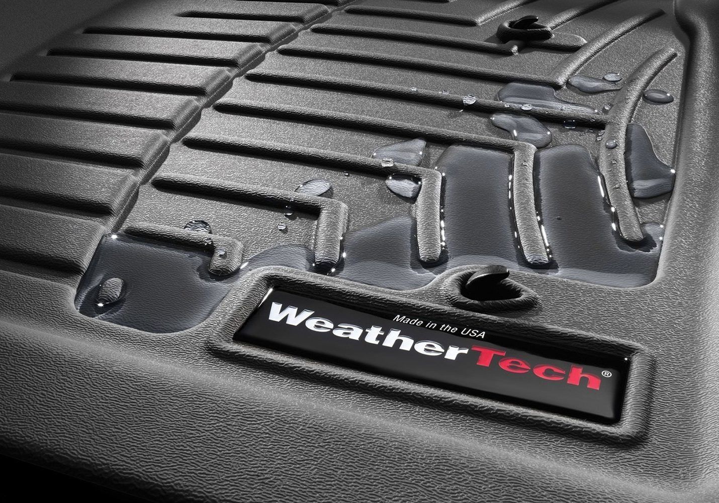 Black WeatherTech car floor mat with water, logo visible.