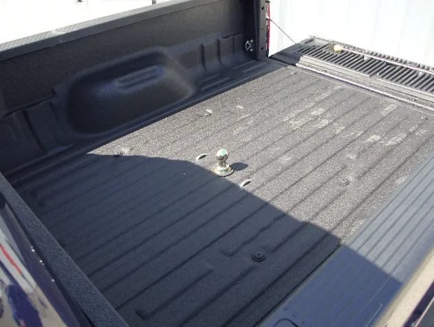 Truck bed with a gooseneck hitch installed, coated in black bedliner.