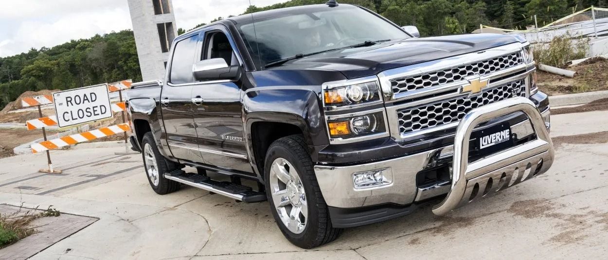 Dark blue Chevrolet Silverado truck with a silver front grill and bull bar parked near a road closed sign.