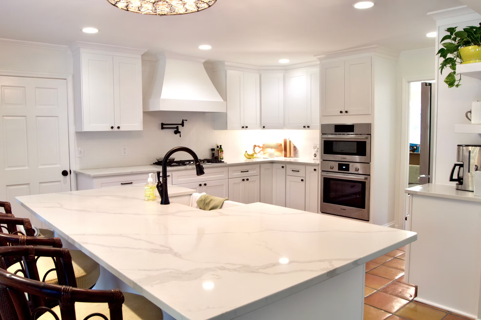 Bright, modern kitchen with white cabinets, marble countertops, and a large island with seating.