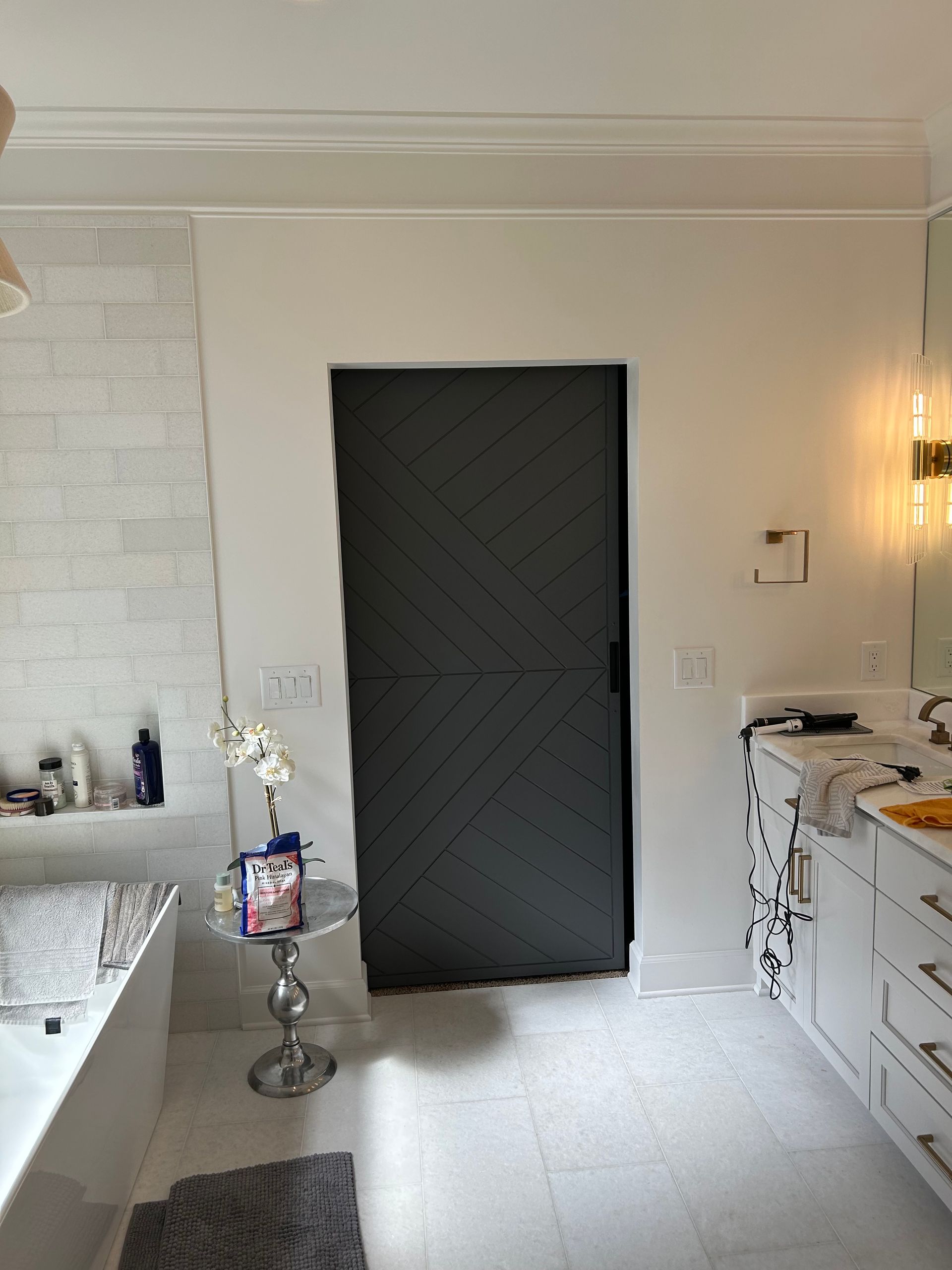 A bathroom with a black door and white cabinets