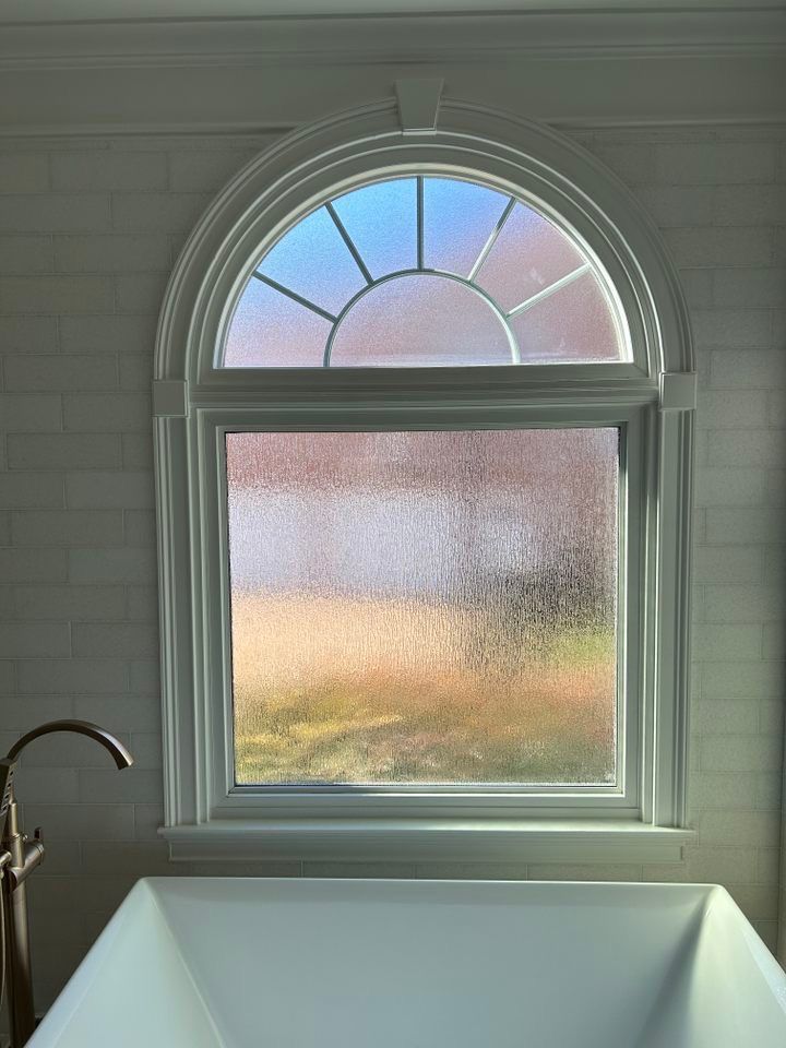 A bathroom with a bathtub and a window with a stained glass window.