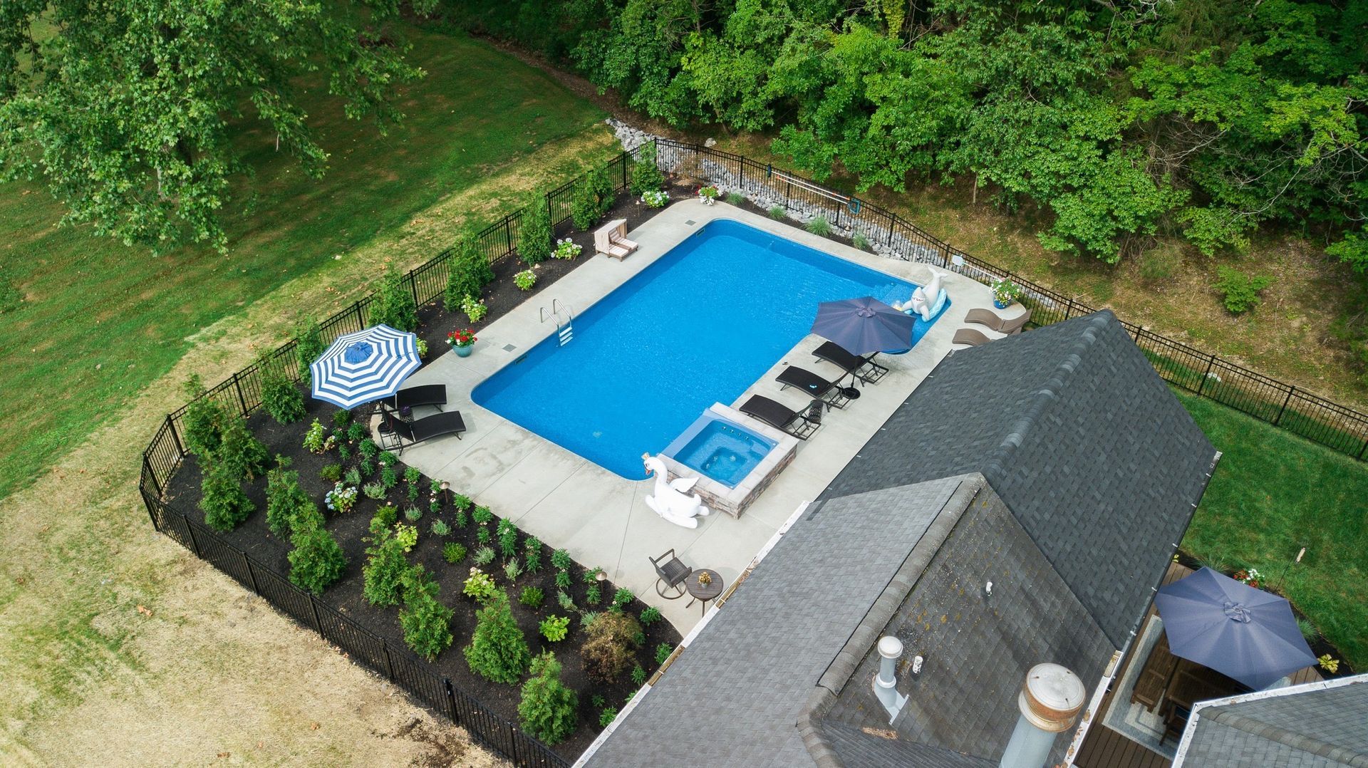 An aerial view of a large swimming pool in the backyard of a house.