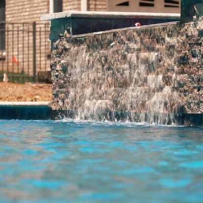 A waterfall is in the middle of a swimming pool.