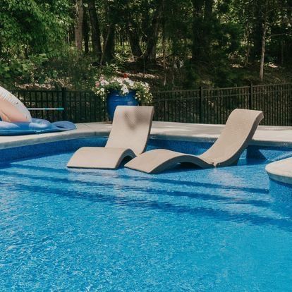 Two lounge chairs are floating in a swimming pool