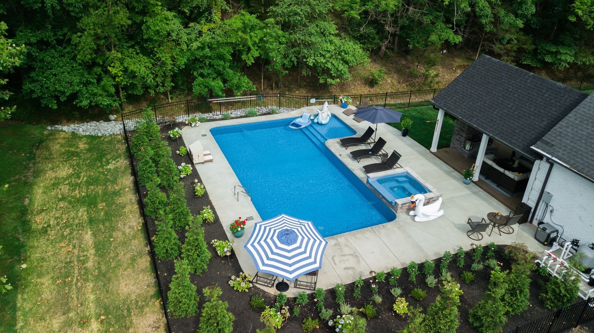 An aerial view of a large swimming pool in a backyard surrounded by trees.