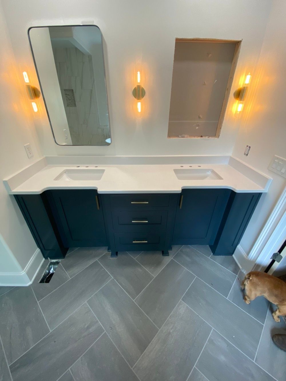 A bathroom with two sinks, a mirror, and lights.