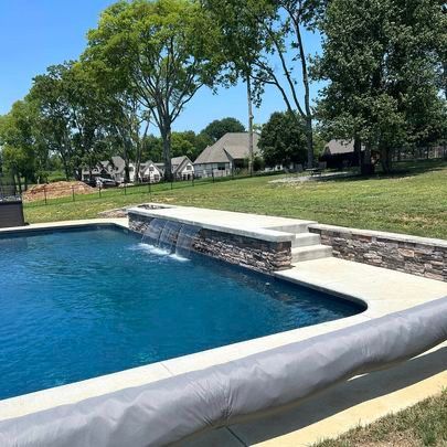 A large swimming pool with a waterfall in the middle