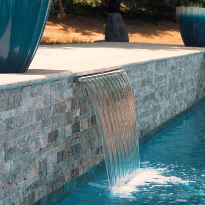 There is a waterfall in the middle of a swimming pool.