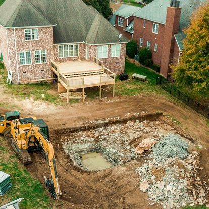 An aerial view of a construction site in front of a brick house.