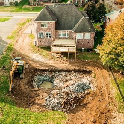 An aerial view of a house under construction with a excavator in front of it.