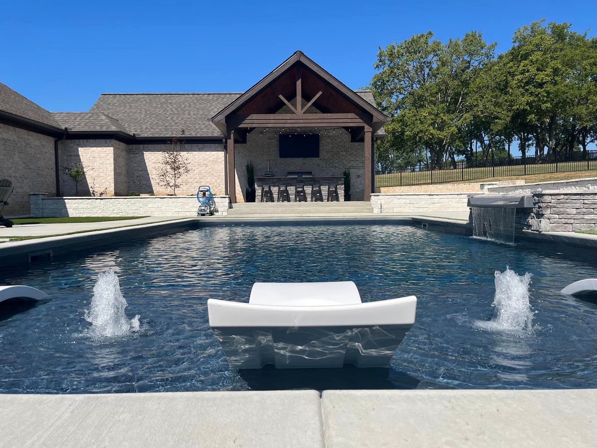 A large swimming pool with fountains in front of a house