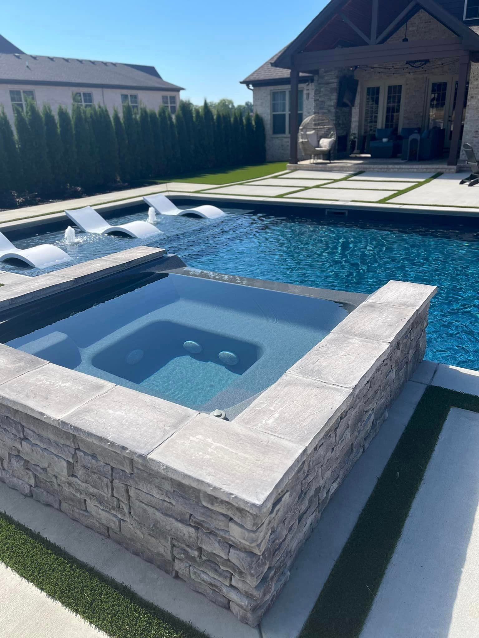 A large swimming pool with a hot tub in the middle of it.