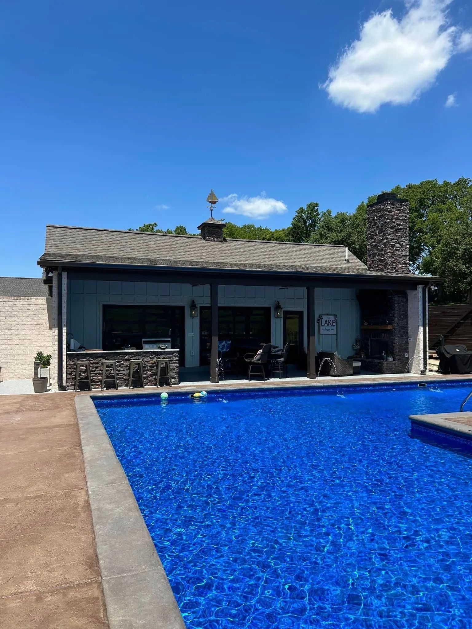 There is a large swimming pool in front of a house.
