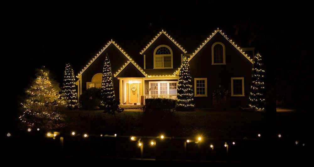 A house at night decorated with yellow Christmas lights.