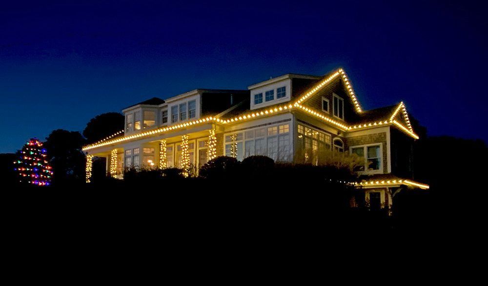 House decorated with yellow Christmas lights against a dark blue sky.