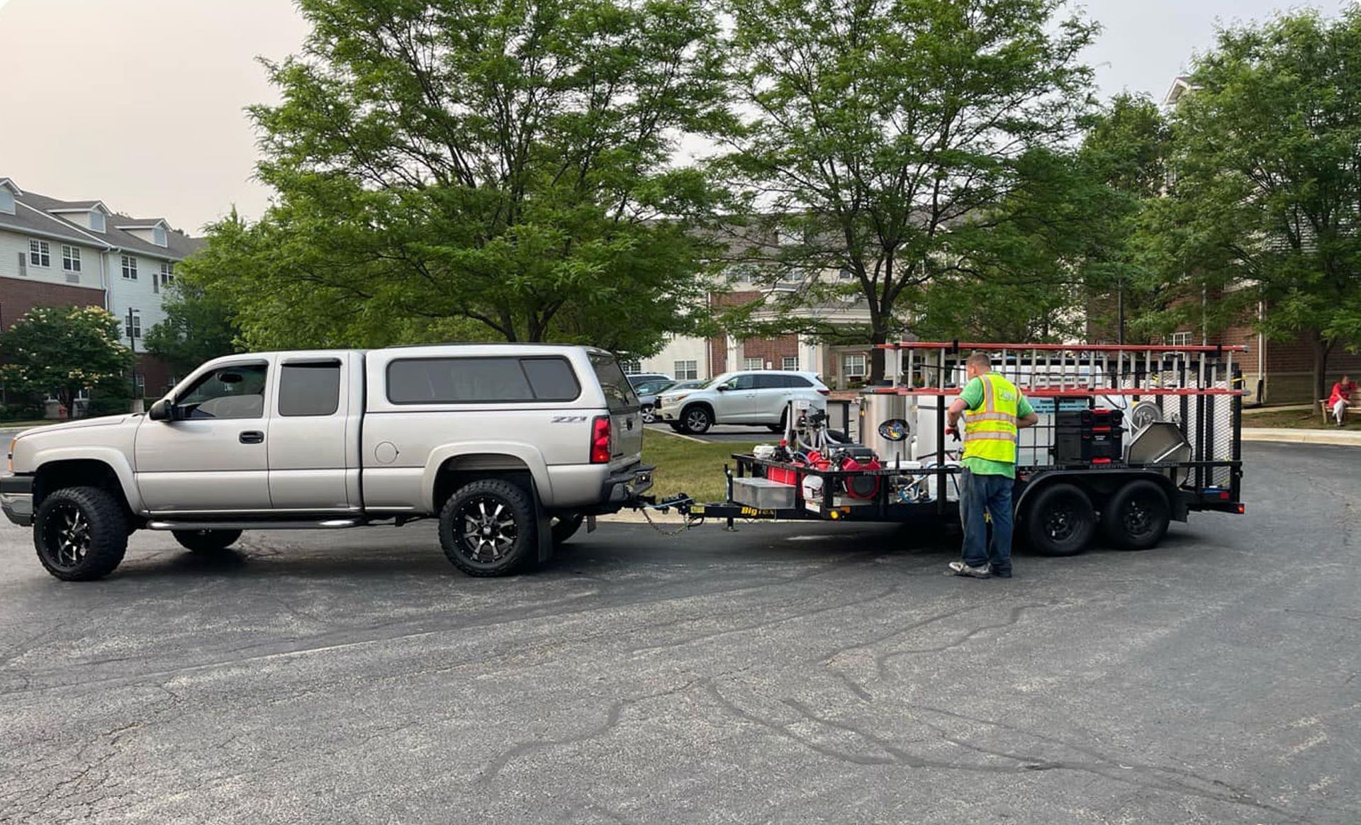 A man is standing next to a truck that is pulling a trailer.