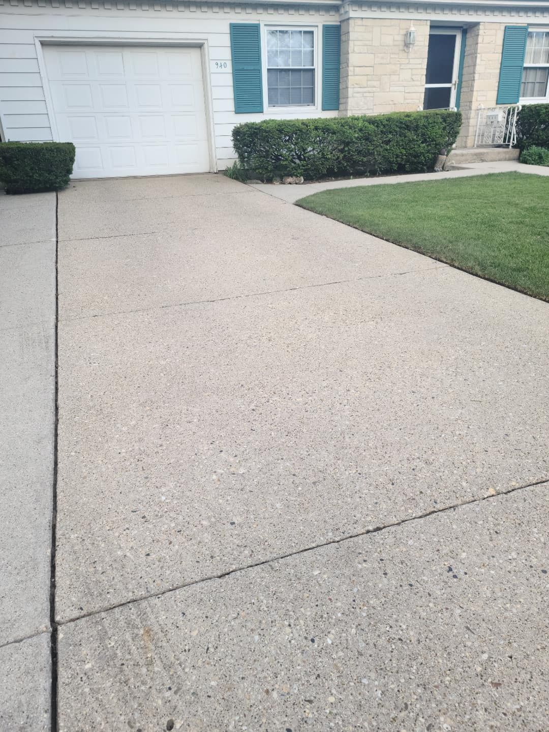 A concrete driveway in front of a house with a garage door.