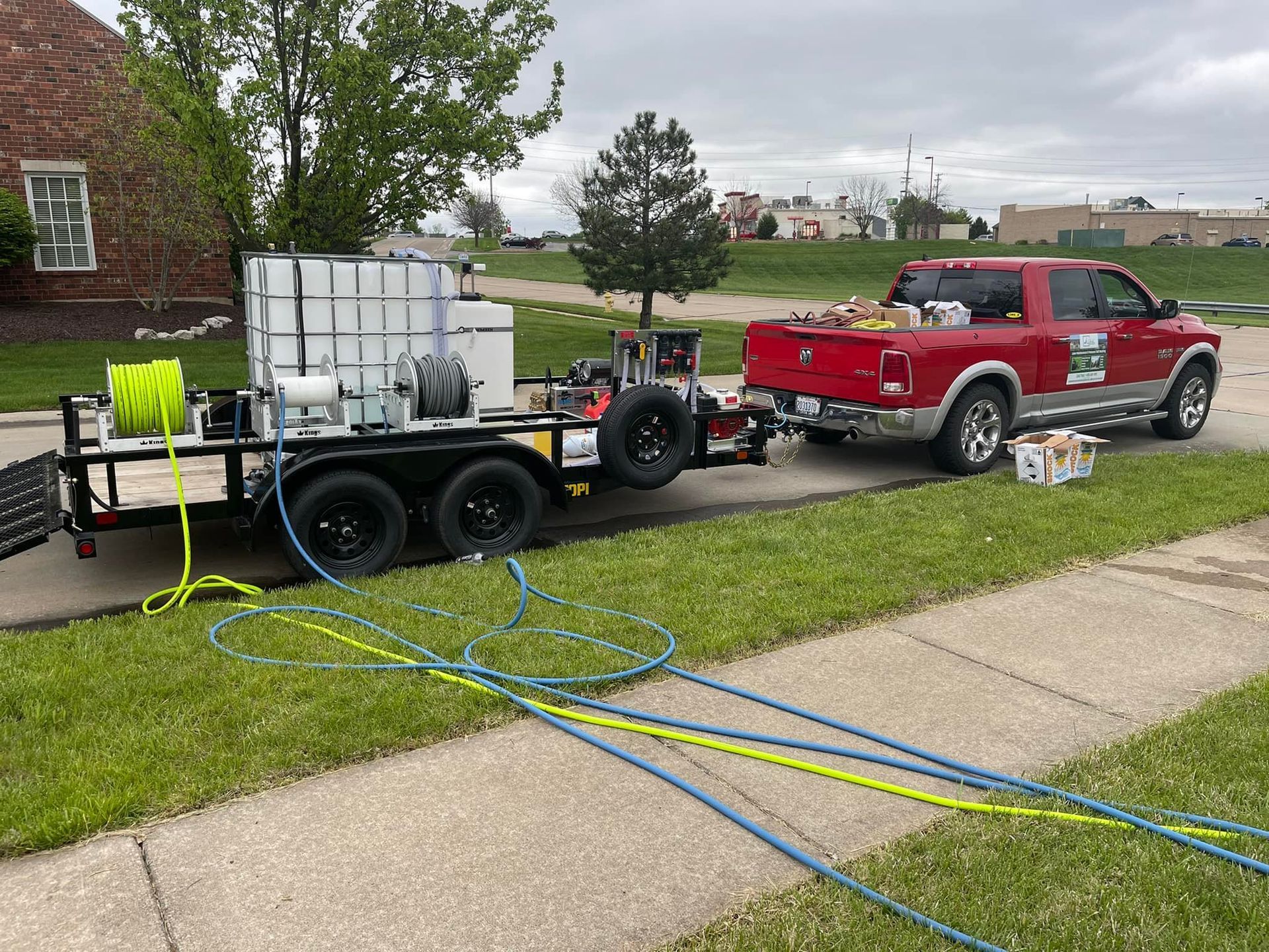 A red truck with a trailer attached to it is parked on the side of the road.