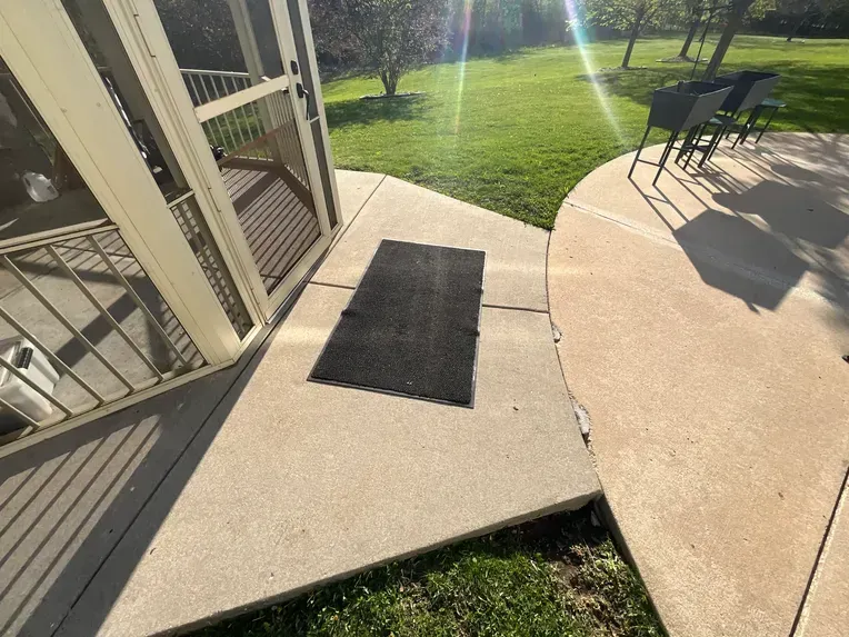 A screened in porch with a black mat on the ground.