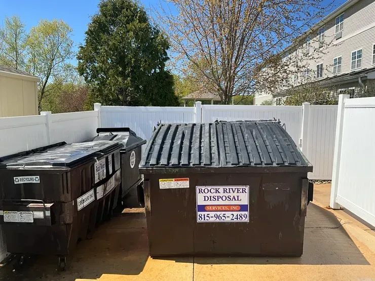 A couple of dumpsters are sitting next to each other in a driveway.