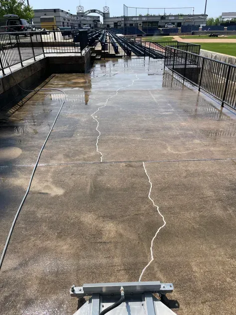 A concrete walkway is being cleaned by a machine.