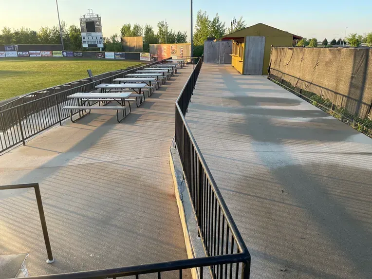 A row of picnic tables in front of a baseball field