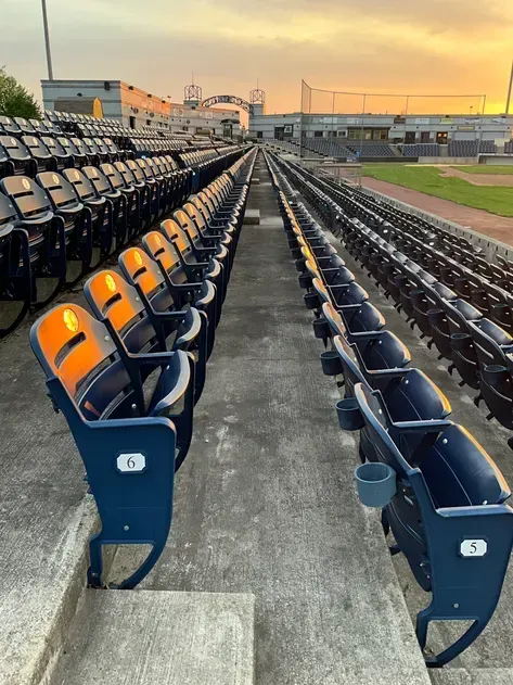 A row of empty seats in a baseball stadium at sunset