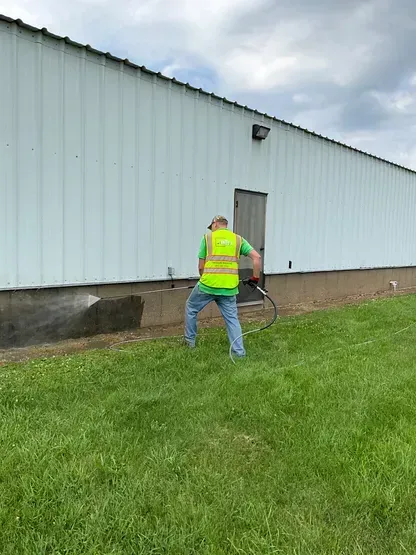 A man is spraying a building with a hose.