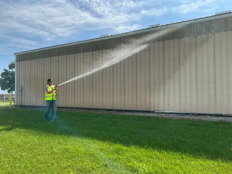 A man is spraying water on the side of a building.