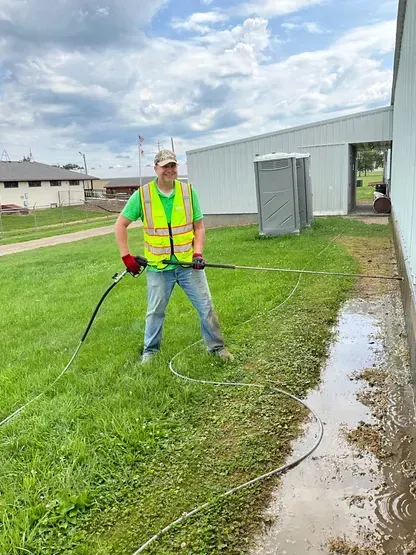 A man is standing in the grass holding a hose.