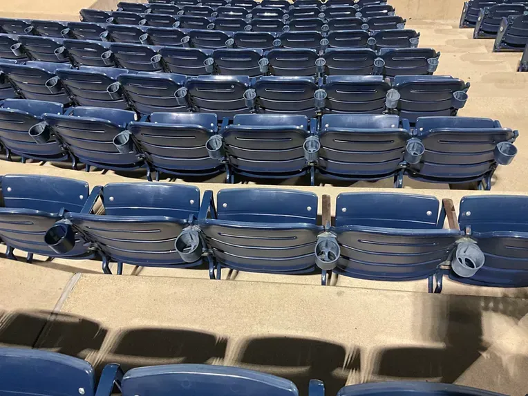 Rows of blue seats are lined up in a stadium.