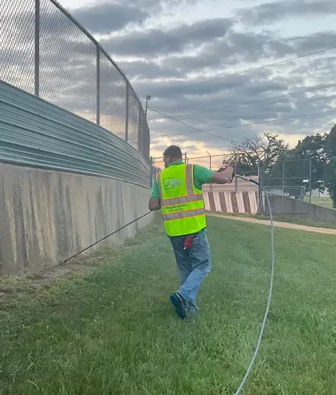 A man in a yellow vest is running in the grass.