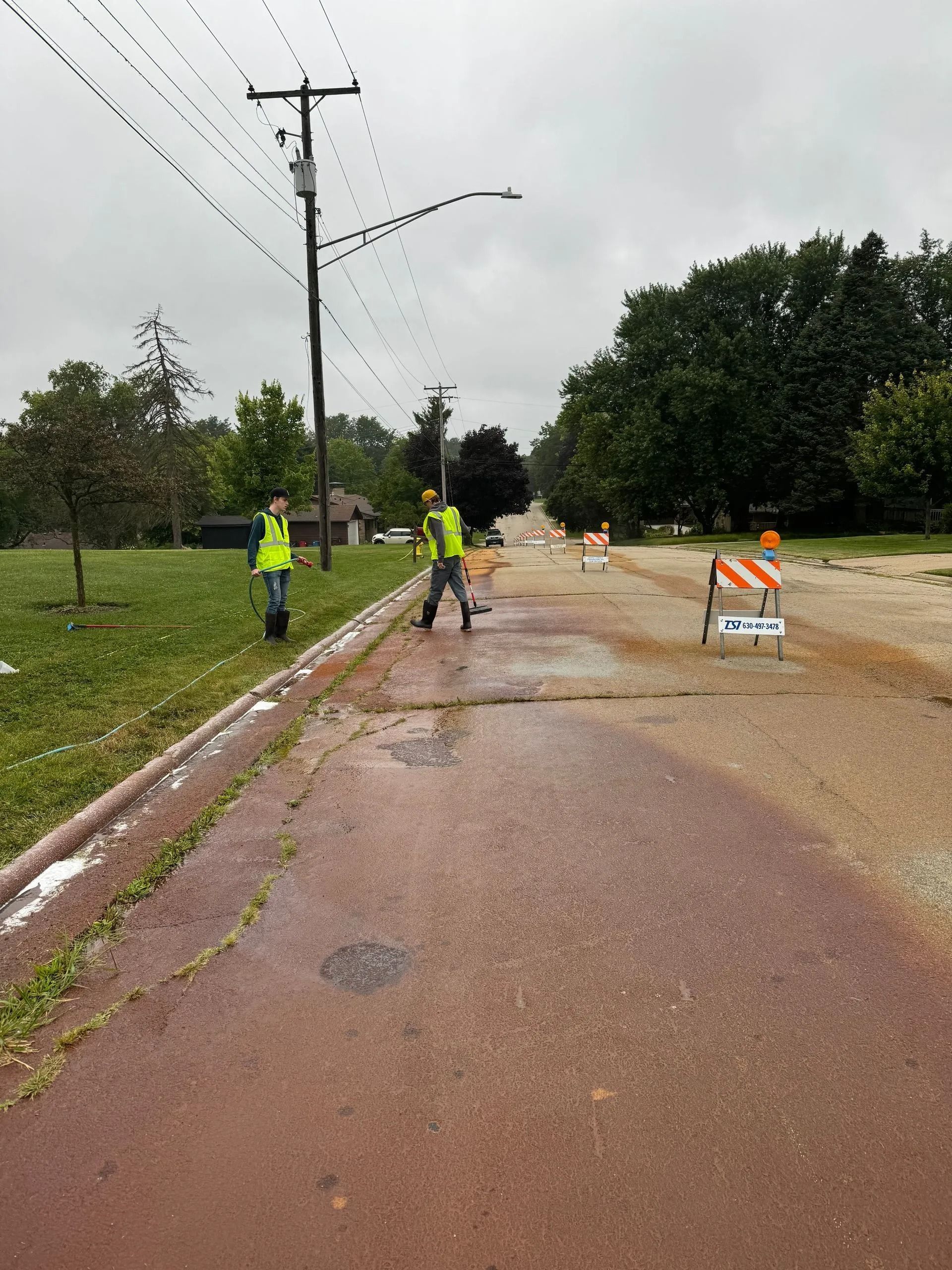 Two men in yellow vests are walking down a flooded street